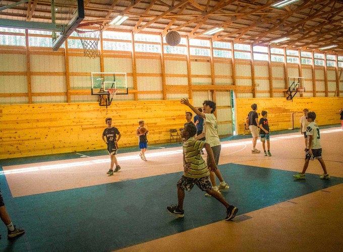 Campers play basketball on the court inside the fieldhouse.