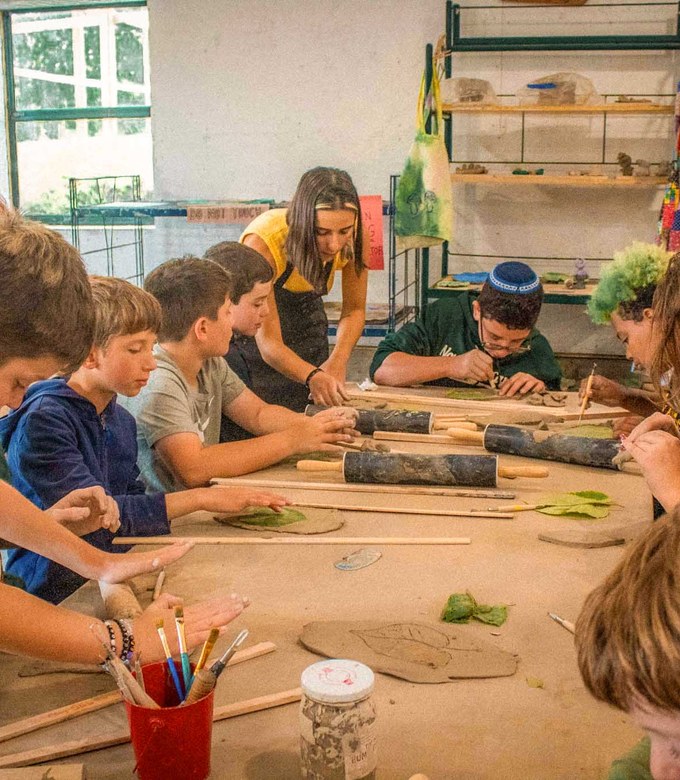 Campers shape clay at the tables in the ceramics studio.