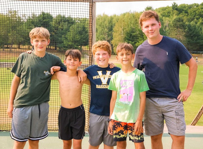 A group of campers stand together smiling outside.
