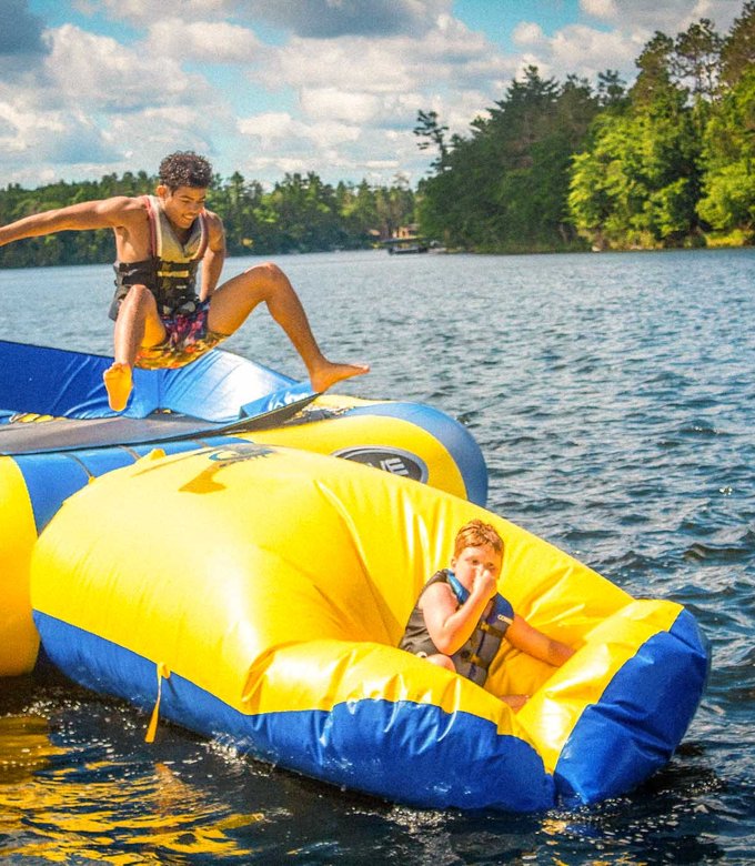 Campers climb and jump off the water trampoline on Spider Lake.