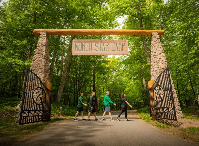 The four North Star Camp directors walk together under the camp entrance arch.