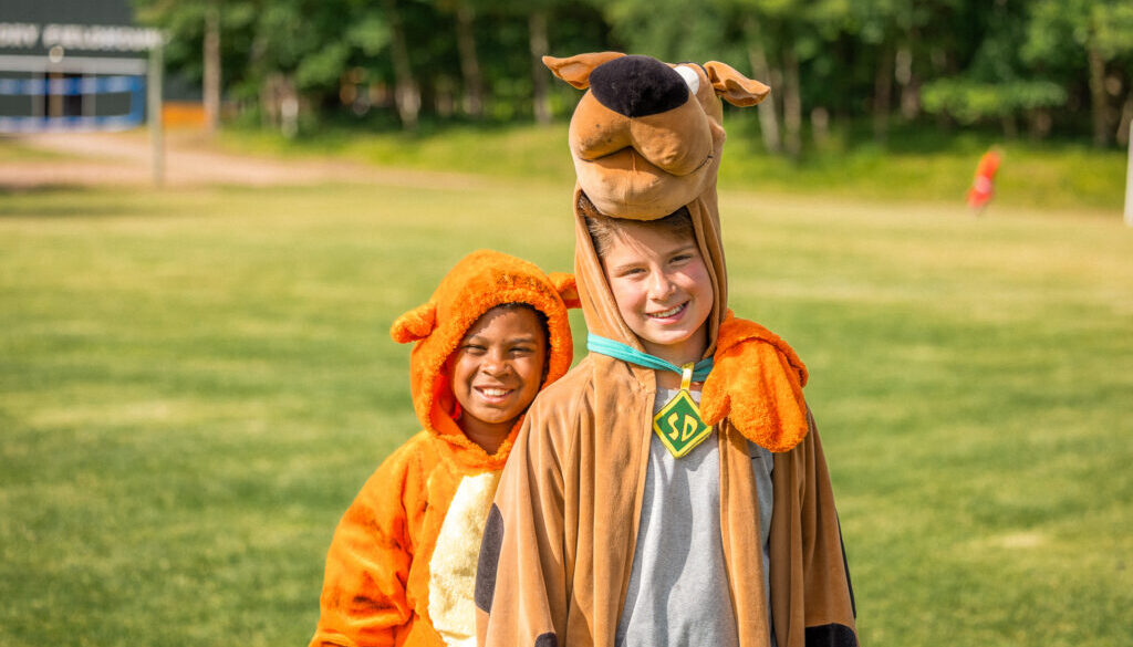 Two smiling North Star campers in costumes on the camp field