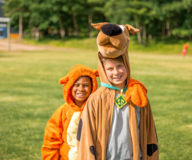 Two smiling North Star campers in costumes on the camp field